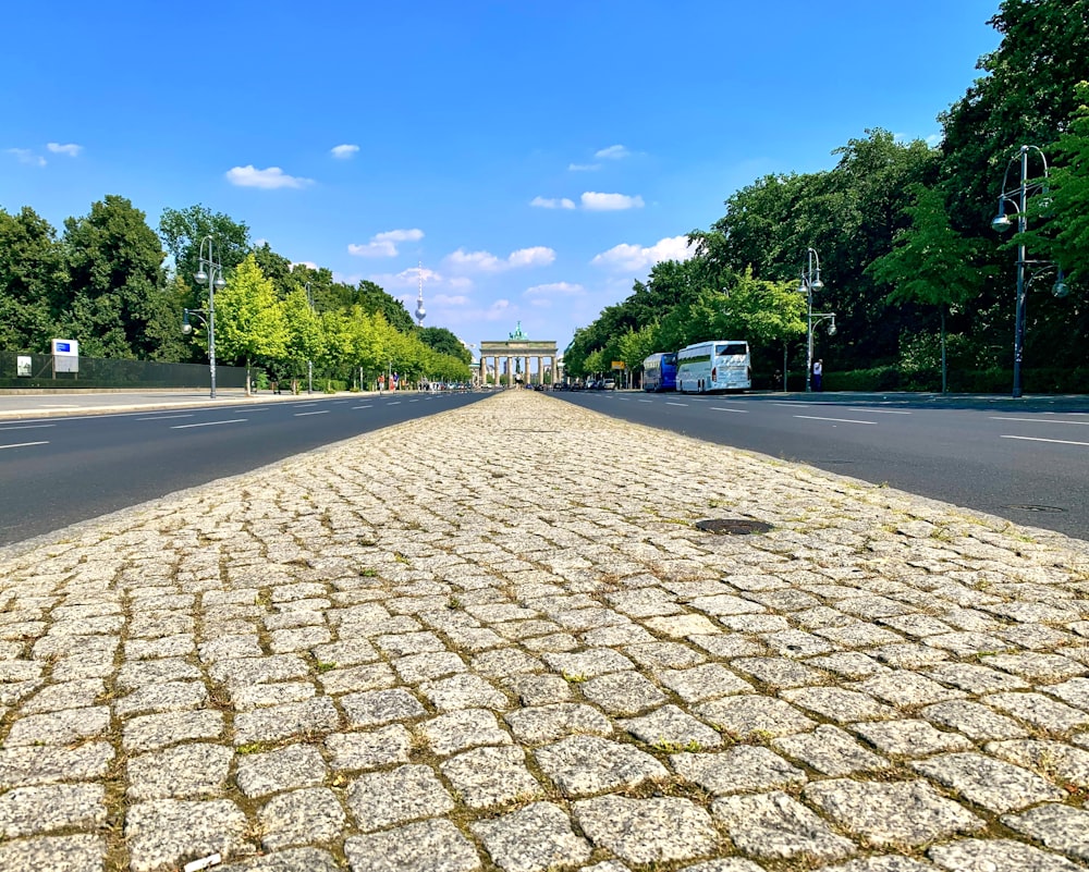 昼間の青空の下、緑の木々の間にある灰色のコンクリート道路