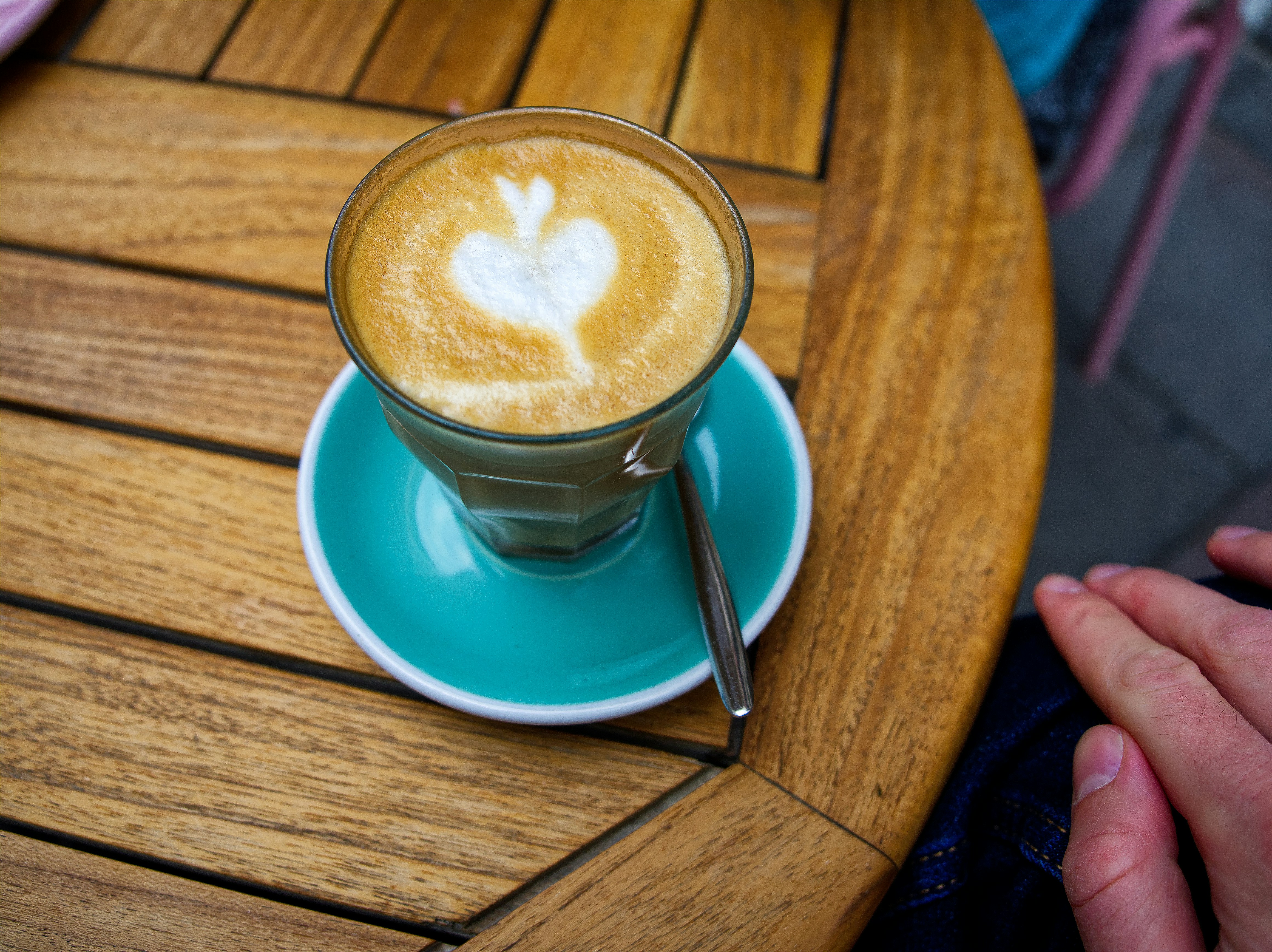 Glass latte on a blue saucer on an outdoor table