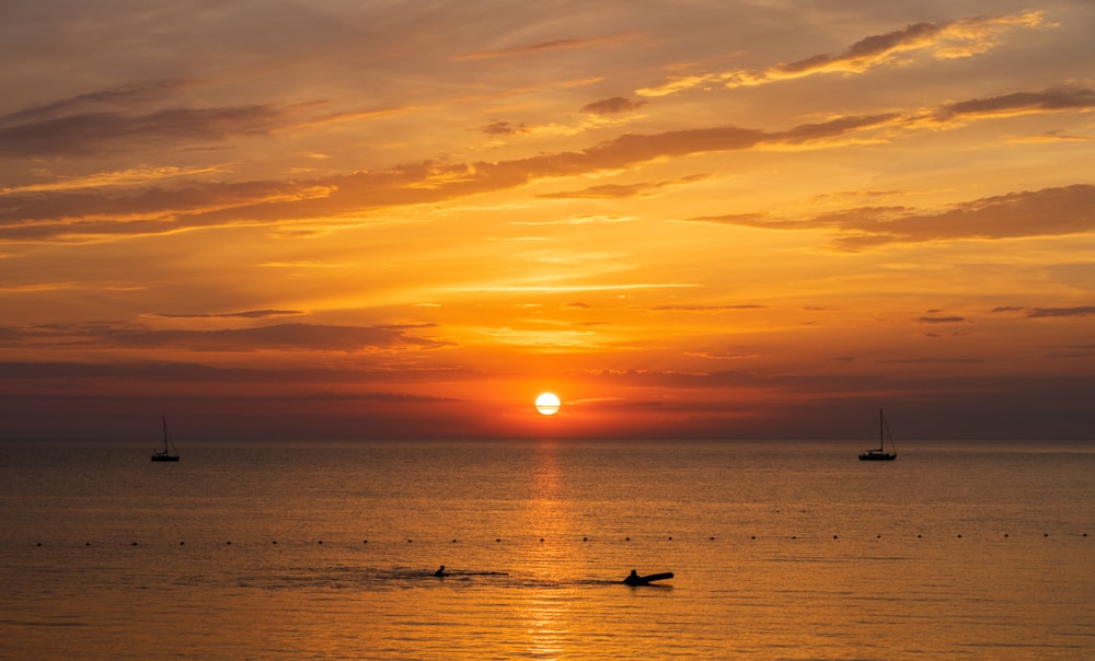 silhouette of person on body of water during sunset