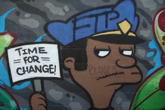 A graffiti artwork depicts a solemn-faced police officer holding a sign that reads 'TIME FOR CHANGE!' The background is filled with shades of gray and some sporadic blue and red elements. The officer's uniform includes a blue hat with a yellow badge.