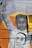 A mural depicts a young African American girl raising her fist in a gesture of power and solidarity. Her facial expression is serious and resolute. She has long braids and is wearing a sweatshirt that bears the face of a man with the words 'I CAN'T BREATHE' written across his mask. The background is an orange circle that contrasts with the monochrome tones of the mural.