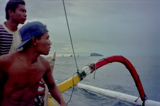 man in blue cap and blue cap riding on boat during daytime in Lovina Beach Indonesia