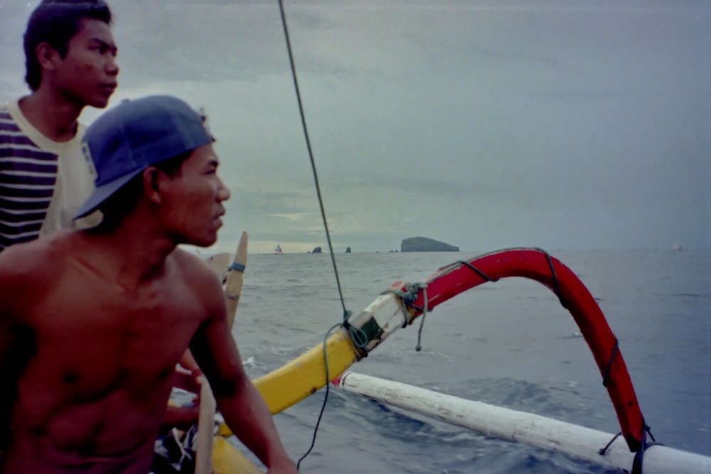 man in blue cap and blue cap riding on boat during daytime