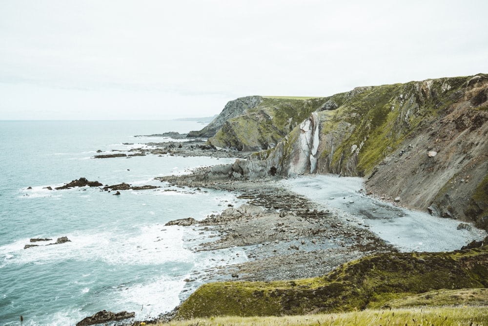 green and brown mountain beside sea during daytime