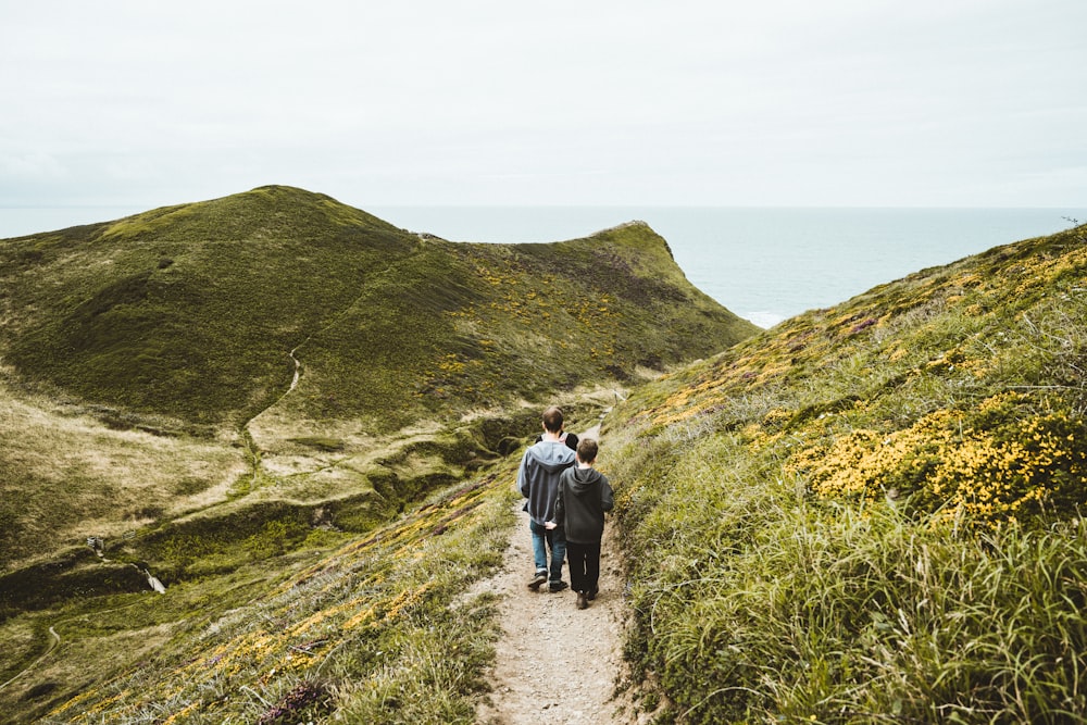 2 person walking on green grass field during daytime