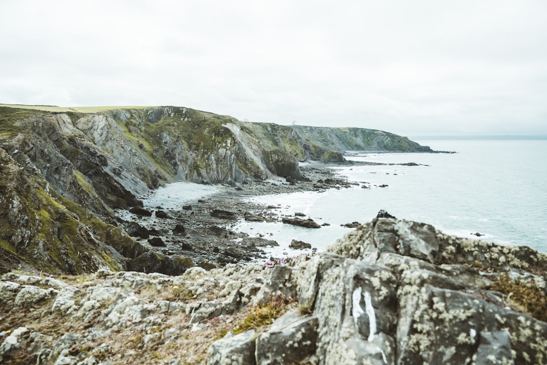 green and gray rock formation near body of water during daytime