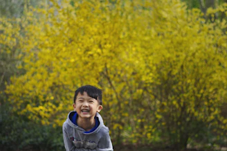 A cheerful child wearing a bright hoodie, jumping in a park on a crisp day.