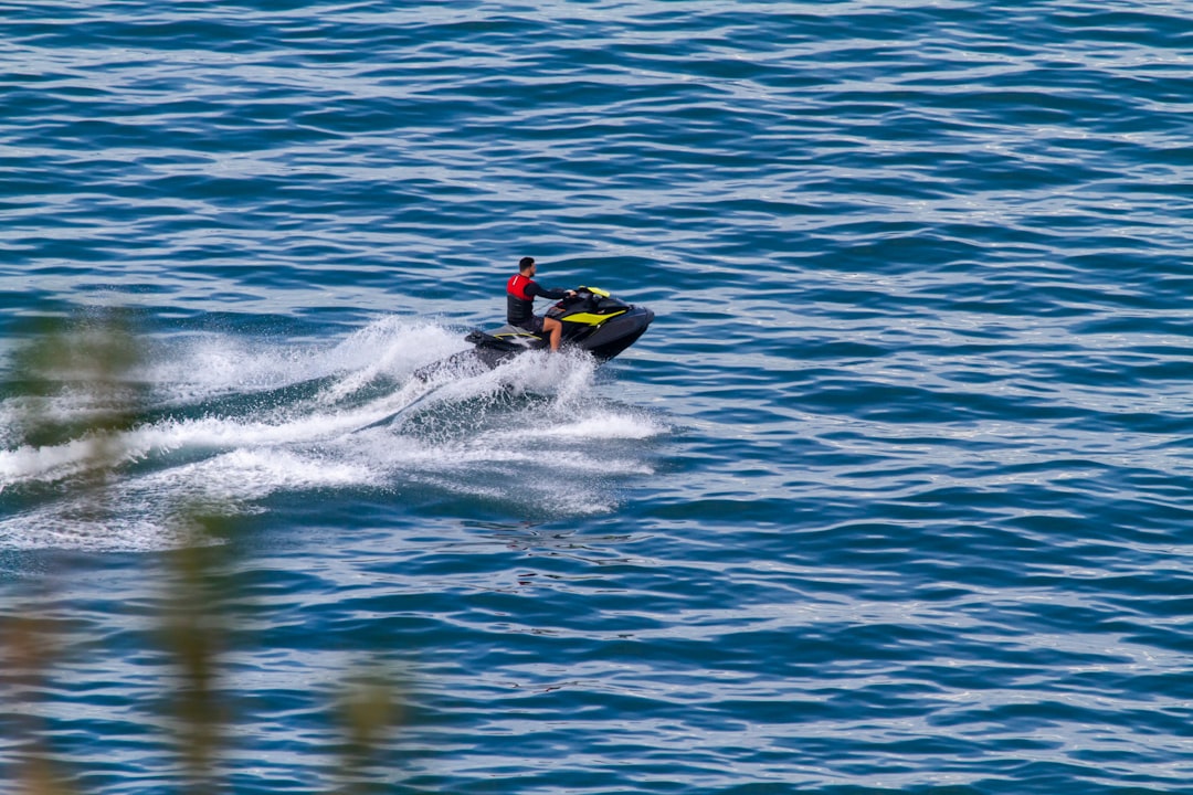 person riding on yellow and black inflatable boat on blue sea during daytime