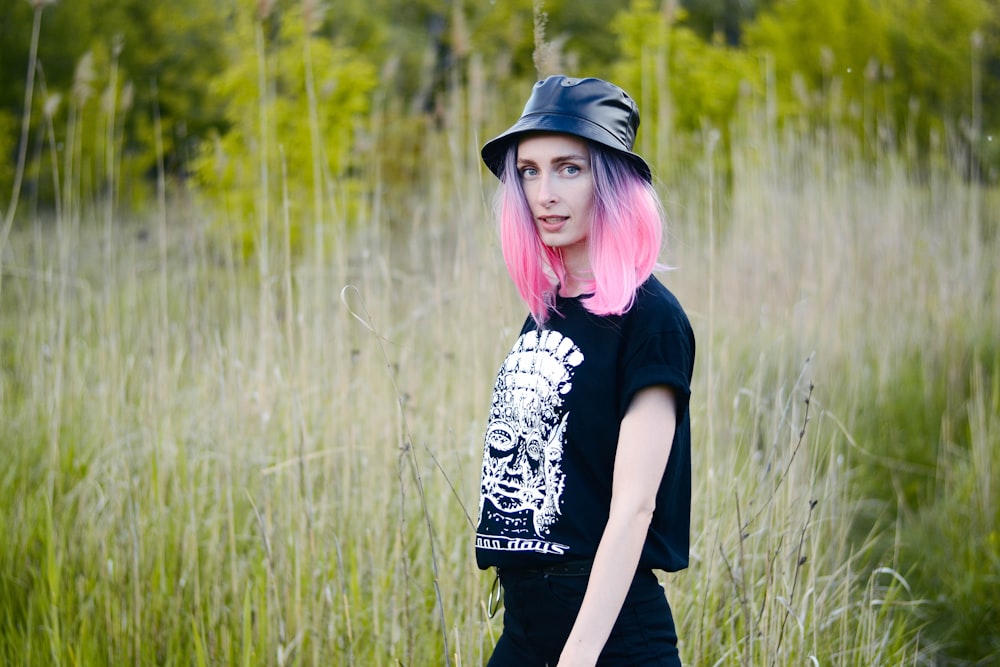 woman in black and white t-shirt standing on green grass field during daytime