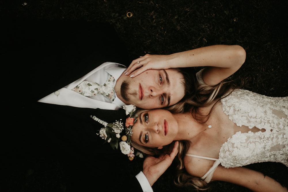 man in black suit jacket beside woman in white floral lace wedding dress