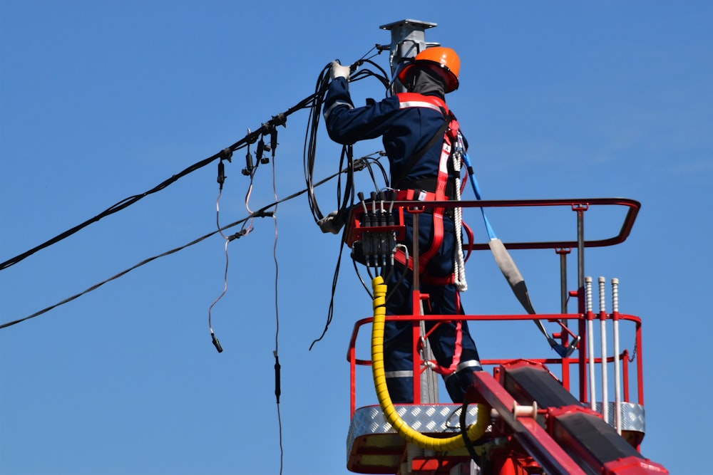 Homme en veste rouge et noire portant un casque orange