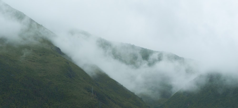 montagna verde coperta di nuvole bianche