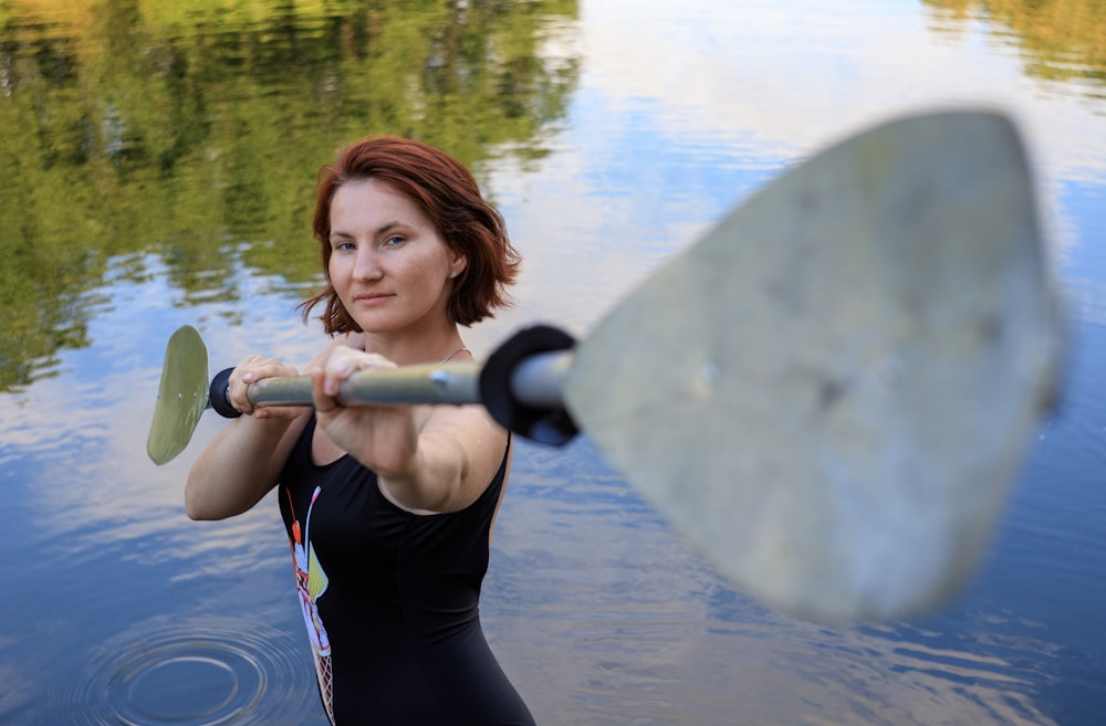 woman in black and red wetsuit holding a white surfboard