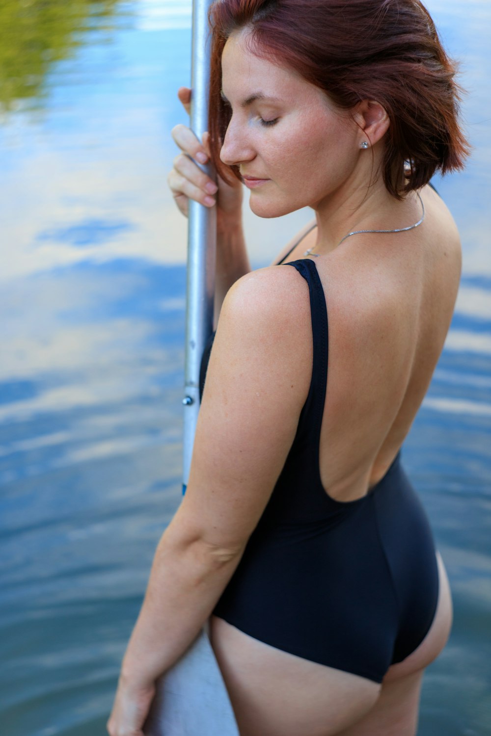 woman in black tank top holding on white metal pole