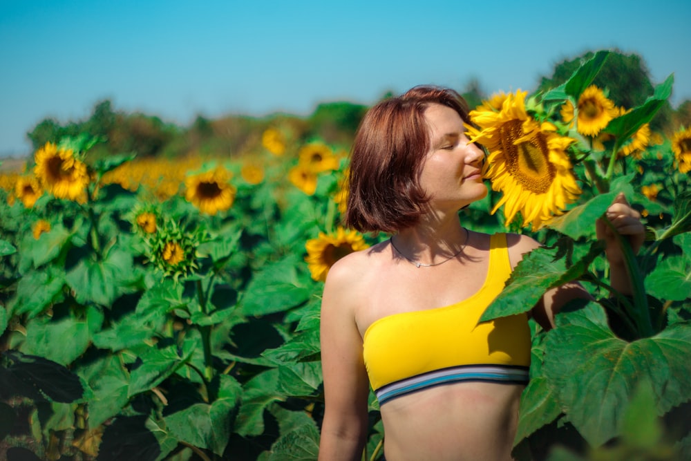 woman in yellow and green bikini top standing on sunflower field during daytime