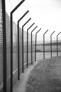 grayscale photo of metal fence