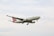 A cargo airplane with the branding 'Turkish Cargo' is flying in the sky. The aircraft is primarily white with red accents on its tail fin. The sky is overcast with light clouds.