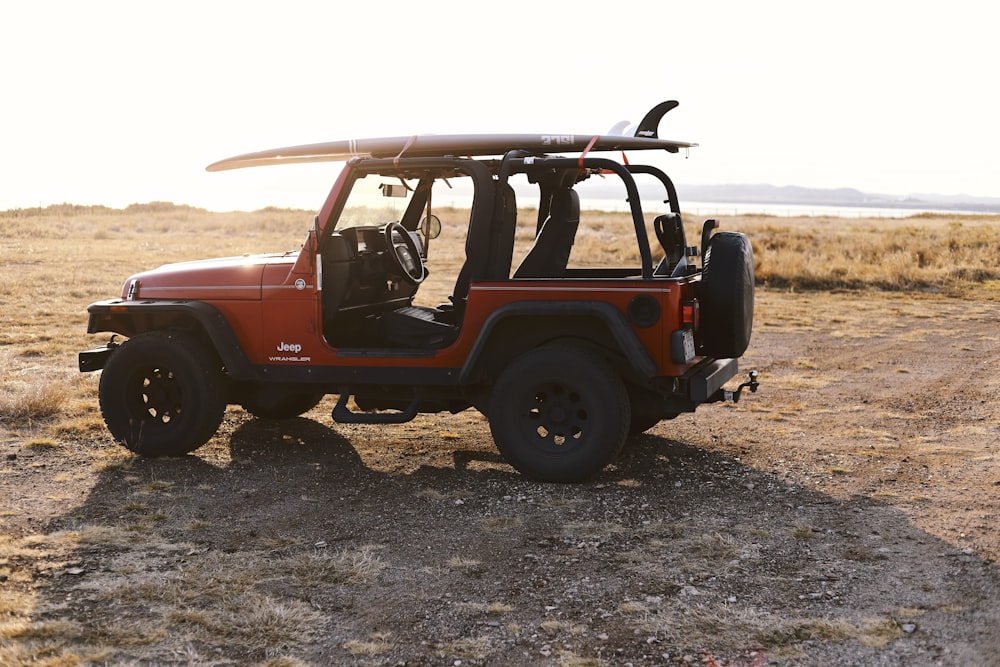 red and black jeep wrangler on brown field during daytime