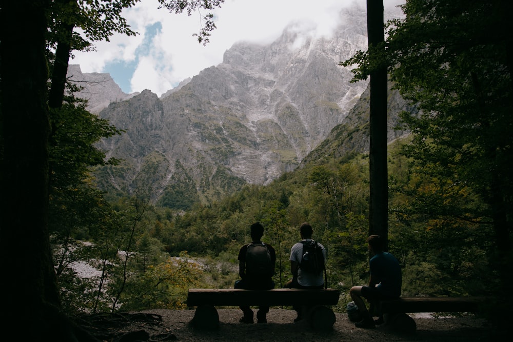 2 person sitting on bench looking at mountain during daytime