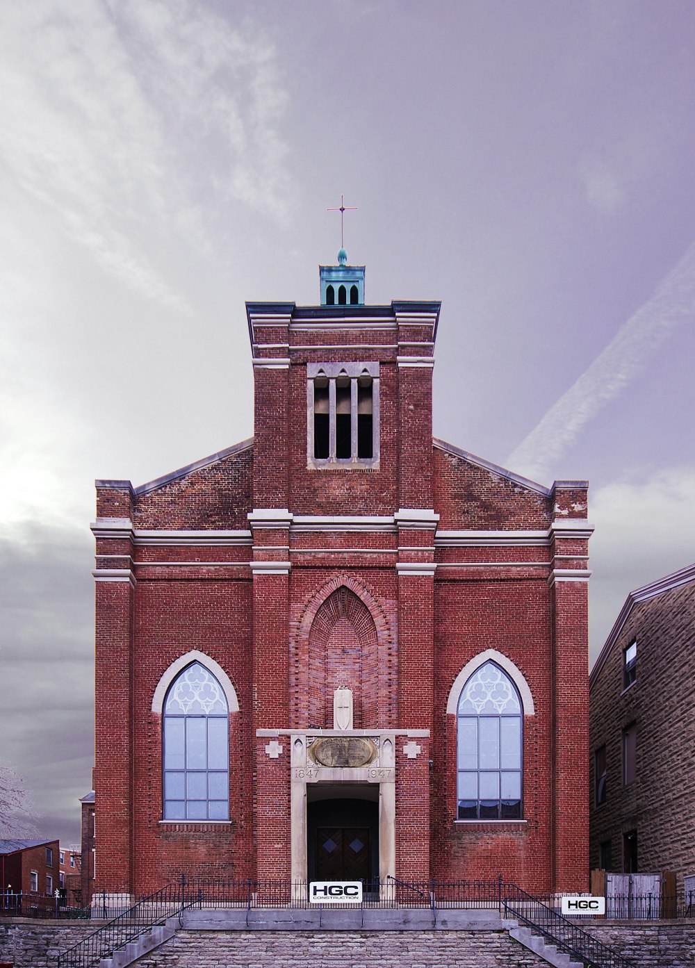 Braune und weiße Betonkirche tagsüber unter weißen Wolken