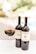 A close-up view of two bottles of wine labeled 'Torrione Petrolo 2015' and a glass filled with red wine. The background appears to be an outdoor setting with blurred greenery and a swimming pool.