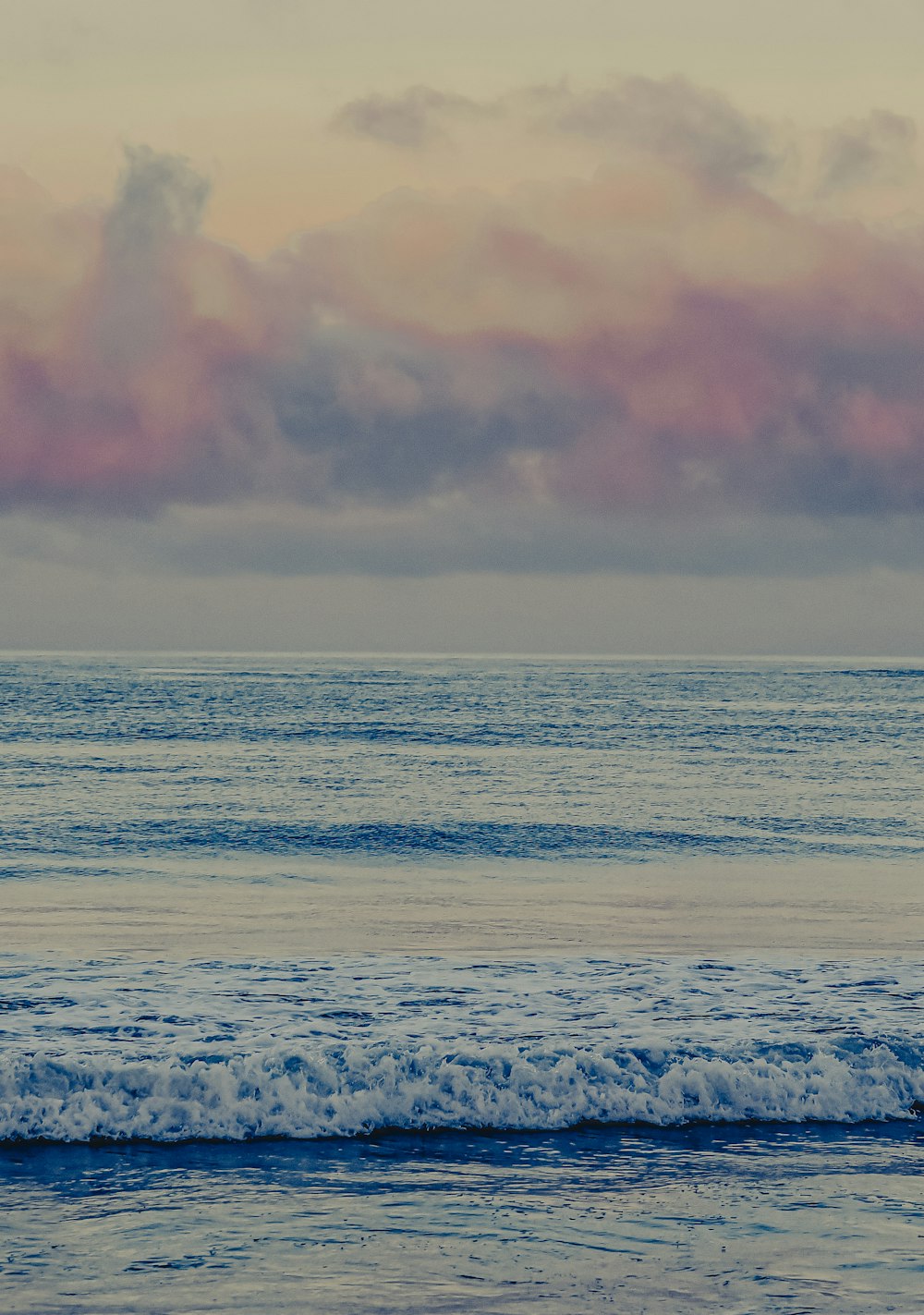 ocean waves crashing on shore during sunset