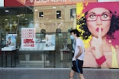 woman in white shirt and black skirt standing near glass window