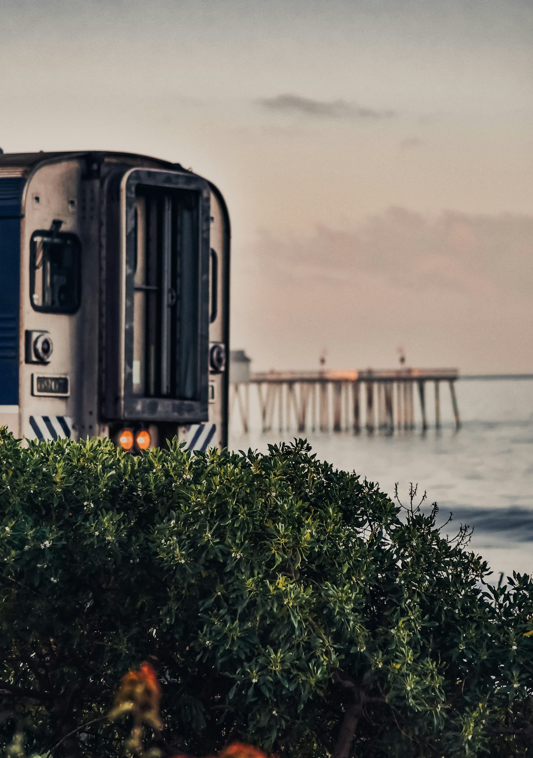 gray train on rail near body of water during daytime