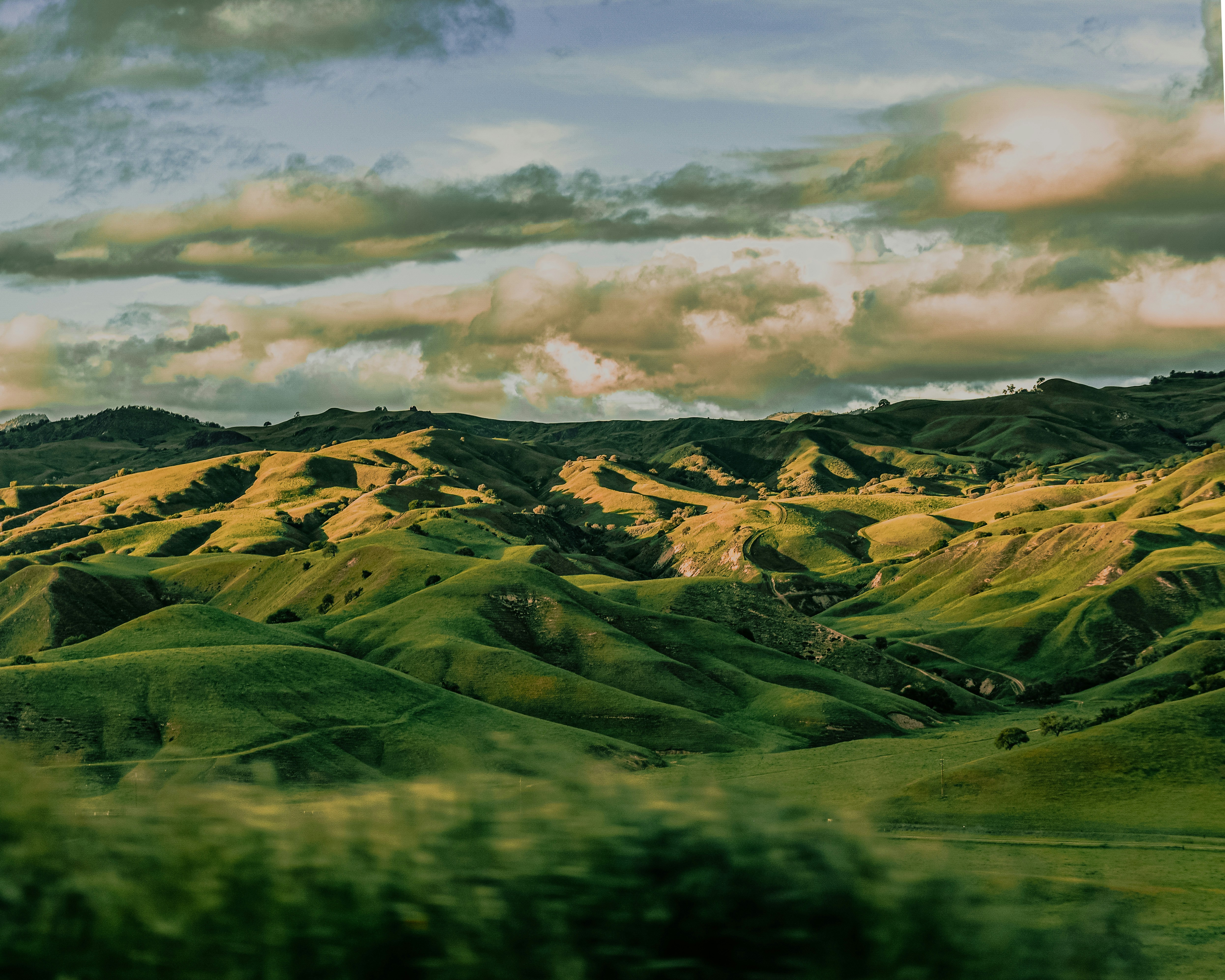 Verdant rolling hills stretch under a partially overcast sky.