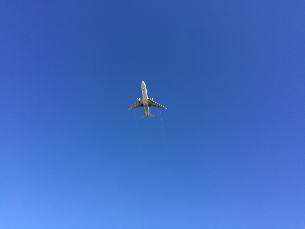 white airplane in mid air during daytime