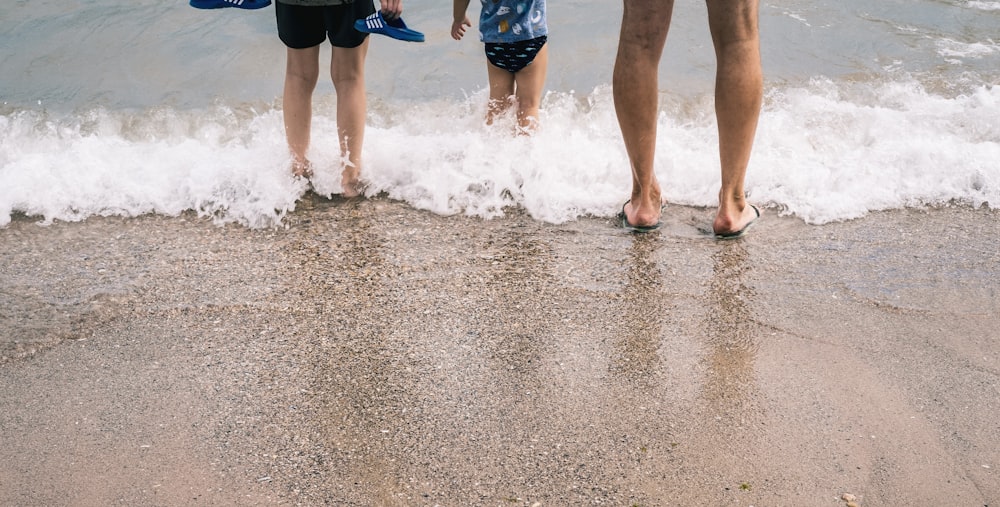 people walking on wet sand during daytime