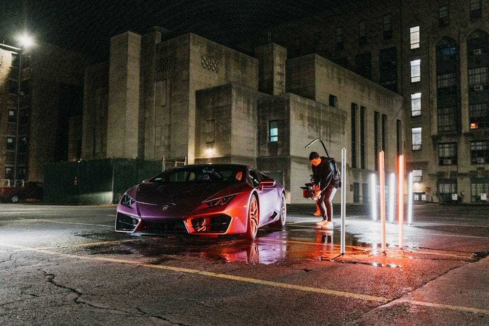 a man standing next to a purple sports car