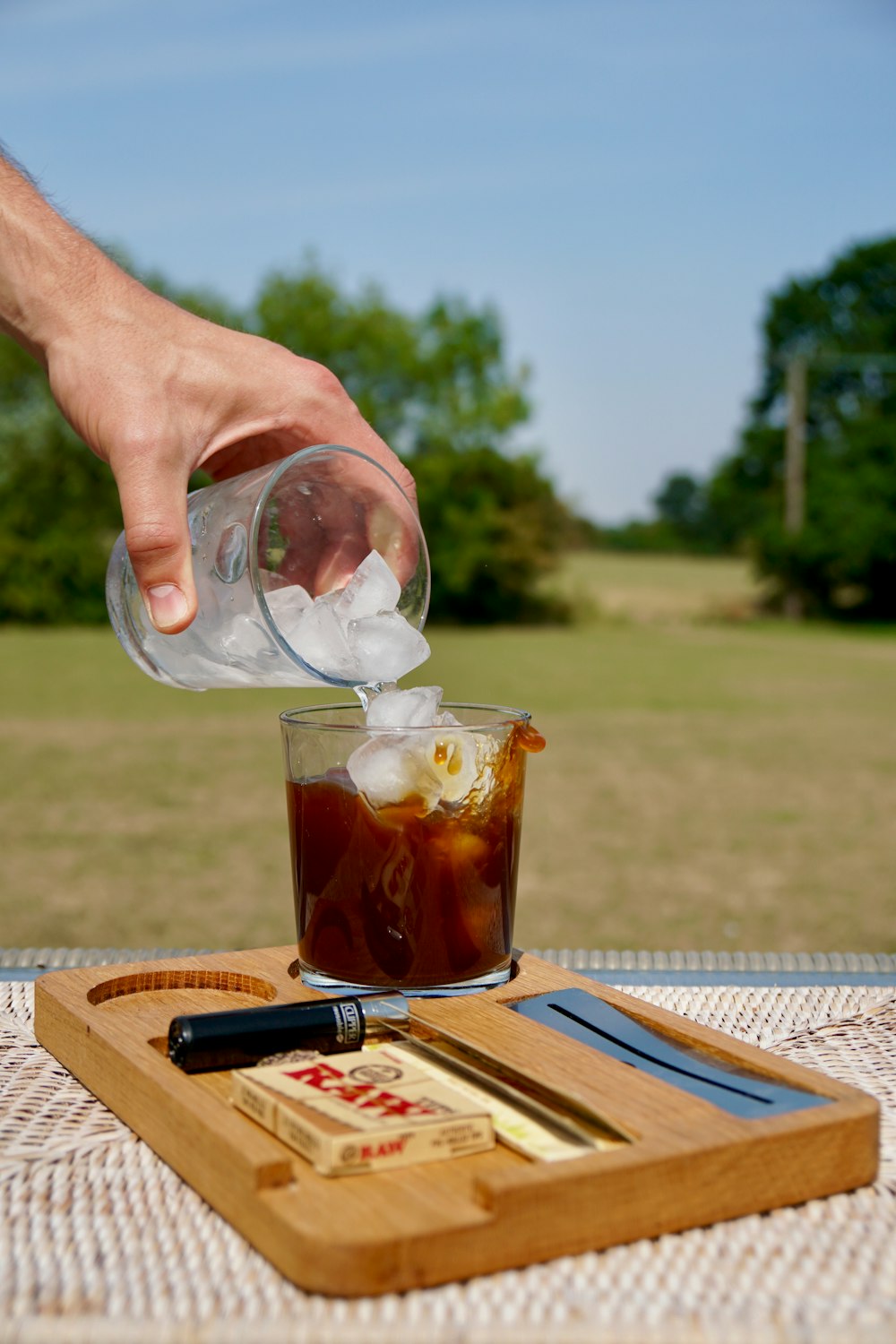 persona sosteniendo un vaso transparente con líquido marrón