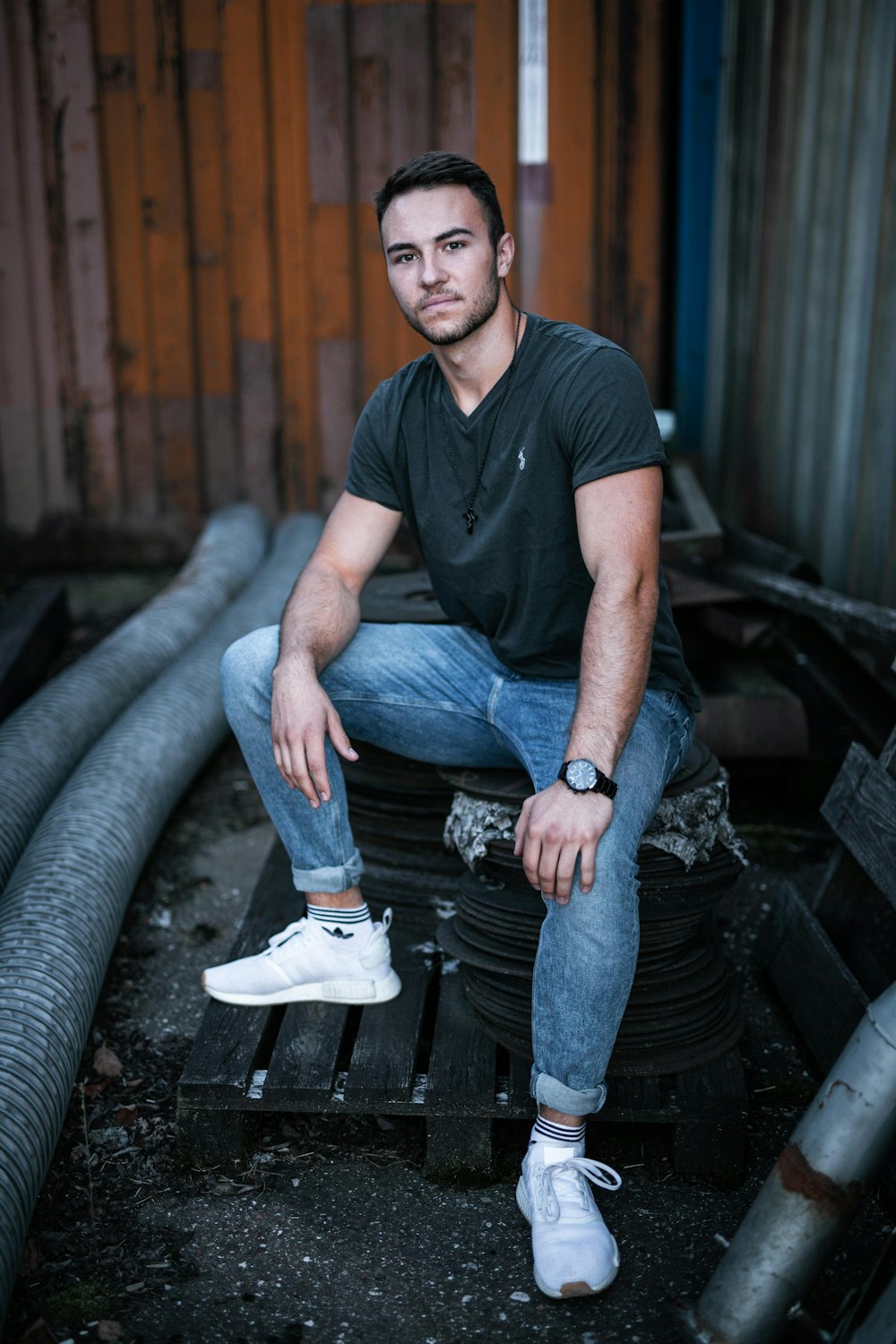 man in black crew neck t-shirt and blue denim jeans sitting on black metal bench