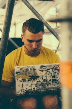 A happy entrepreneur working on a laptop with yellow and black branding elements around.