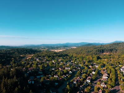 Aerial view of spacious residential lot surrounded by lush greenery under clear blue sky