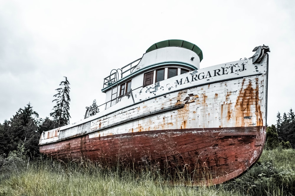 an old rusted boat sitting in a field