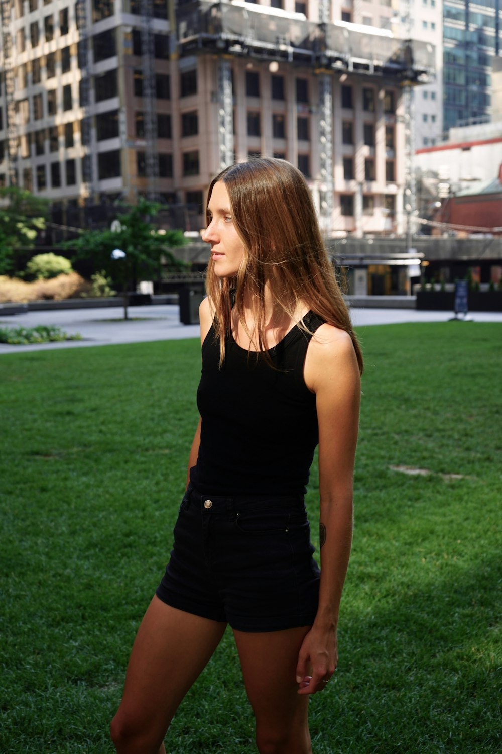 a woman standing in the grass in front of a building
