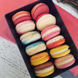 Close-up of vibrant jewel-toned macarons arranged in a delicate emerald green box.