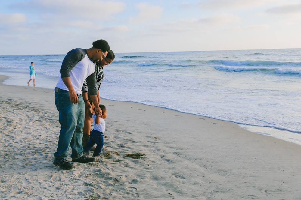 man in blue shirt and blue denim jeans holding woman in white shirt on beach during