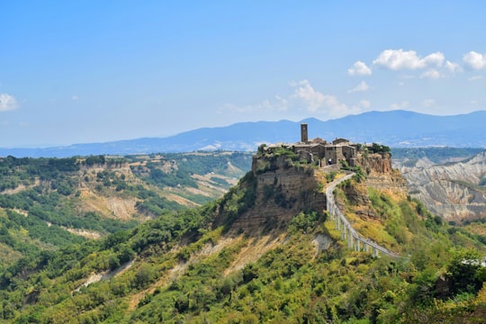 green grass covered hill under blue sky during daytime in Civita di Bagnoregio Italy