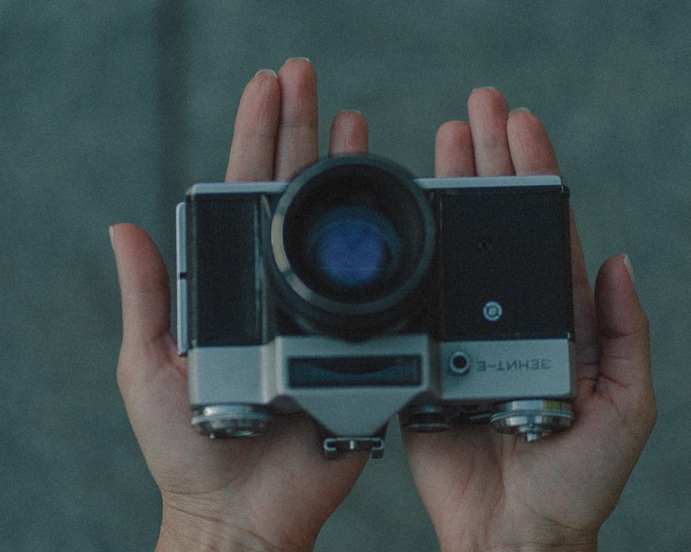 person holding black and silver camera