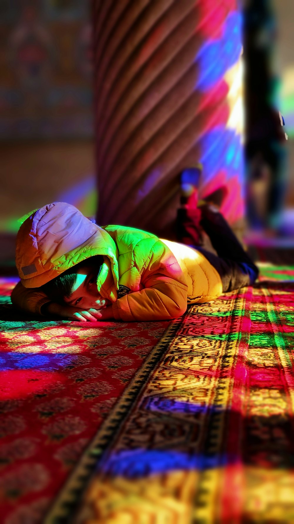 woman in yellow shirt lying on red and brown carpet