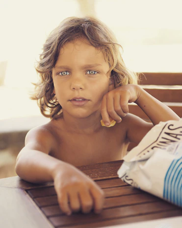 A smiling child enjoying a colorful, healthy snack at a cozy kitchen table.