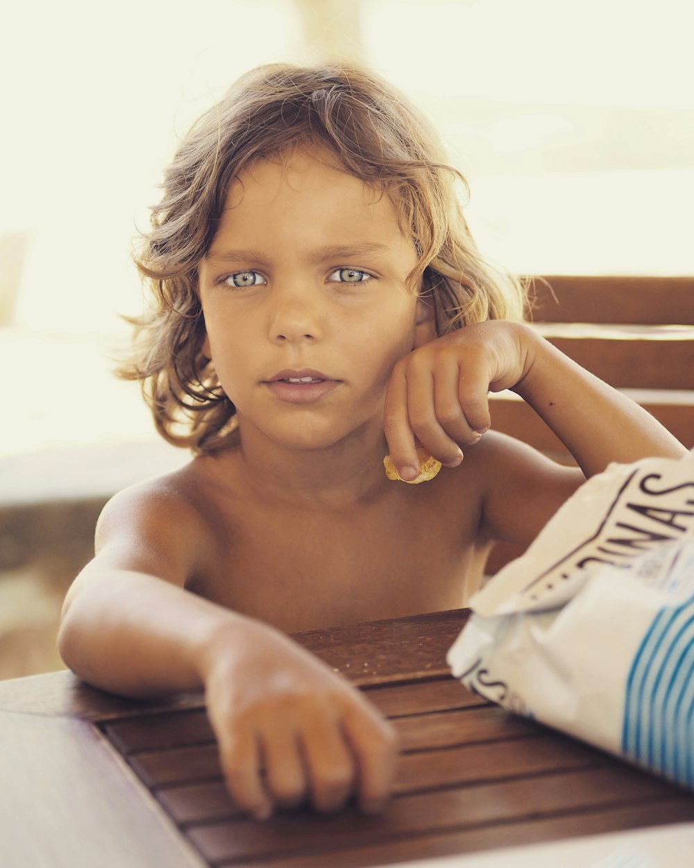 girl in white and blue striped shorts sitting on brown wooden bench