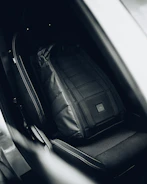 Travel sport sling bag hanging on a car seat handle.