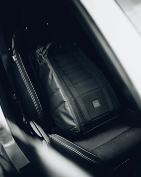 Travel sport sling bag hanging on a car seat handle.