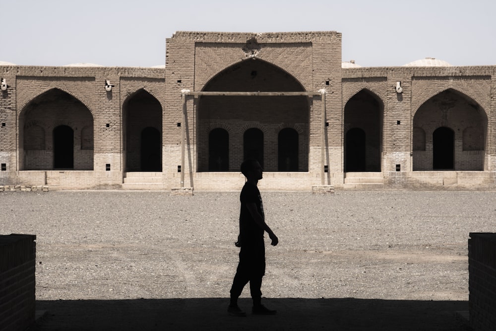 man in black coat walking on brown sand during daytime