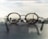 Glasses rest on a surface, with their lenses focusing on a distant cityscape, creating a sharp contrast between the blurred foreground and the clear view through the lenses.