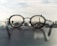 Glasses rest on a surface, with their lenses focusing on a distant cityscape, creating a sharp contrast between the blurred foreground and the clear view through the lenses.